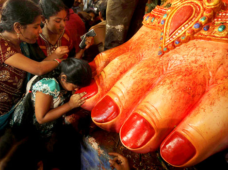 Women kissing the foot of an idol.
